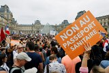 A large crowd of protesters gather in Paris holding French flags and signs rallying against the vaccine passport.  