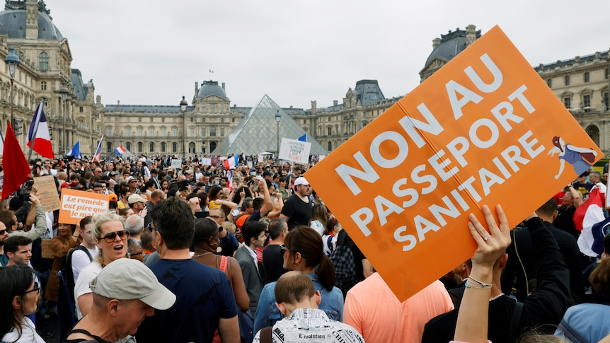 A large crowd of protesters gather in Paris holding French flags and signs rallying against the vaccine passport.  