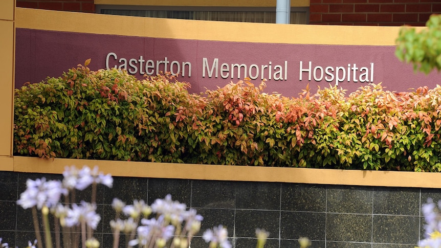 A garden bed and a sign in front of a hospital saying Casterton Memorial Hospital.