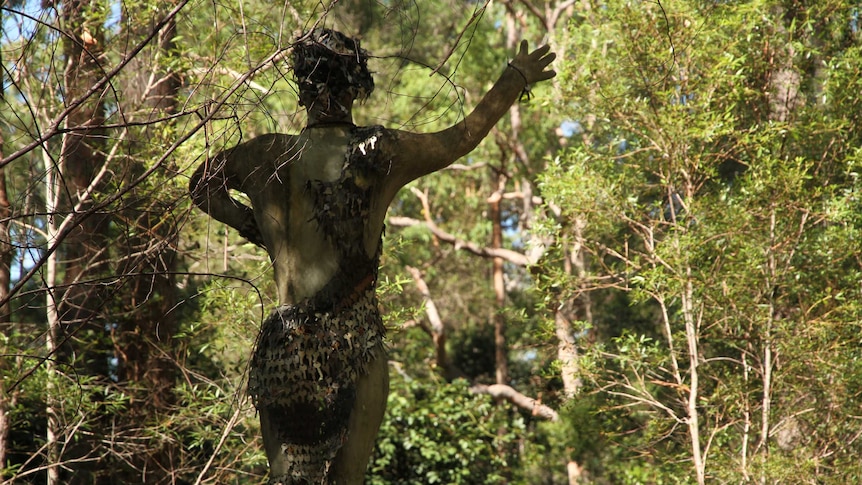 A statue from behind, in the bush