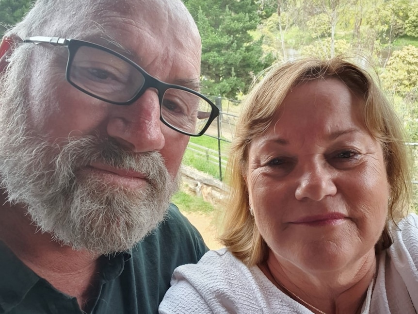 A man with a grey beard and glasses with a blonde woman in a selfie