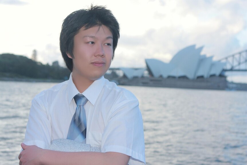 一个中国年轻人站在悉尼港前，远远地看着