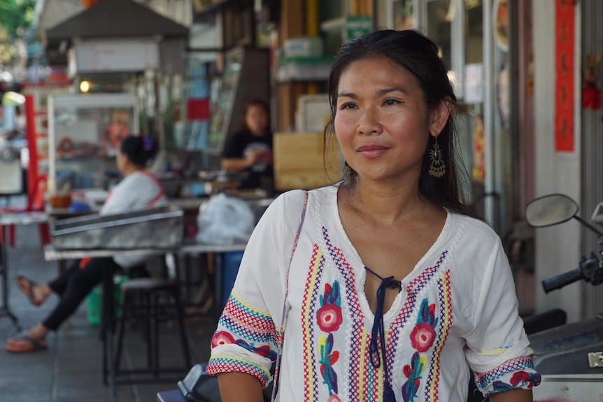 Woman stands in front of street stalls in Bangkok