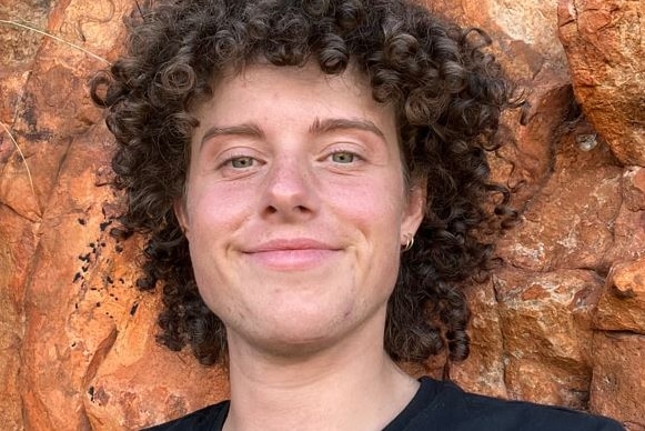 A smiling young man with a mass of dark curly hair.