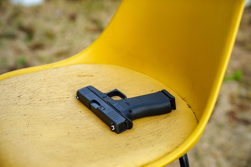 A handgun on a yellow chair.