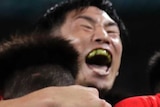 Japan players in red and white striped shirts hug and jump together