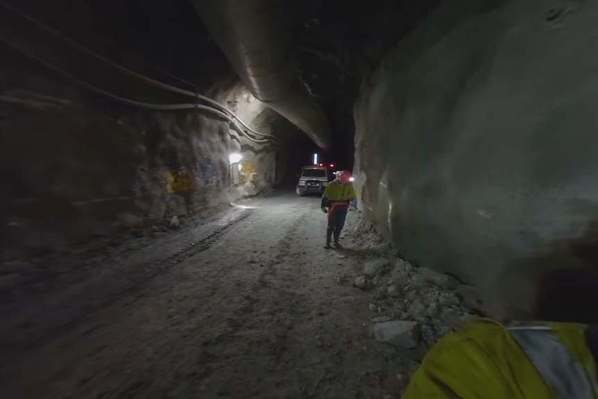 矿井内一条黑暗的隧道，矿工们走过其中。