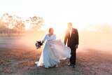 A bride and groom smile at each other in dusty setting