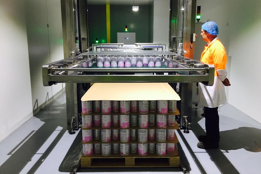 A factory worker operating a canning machine.