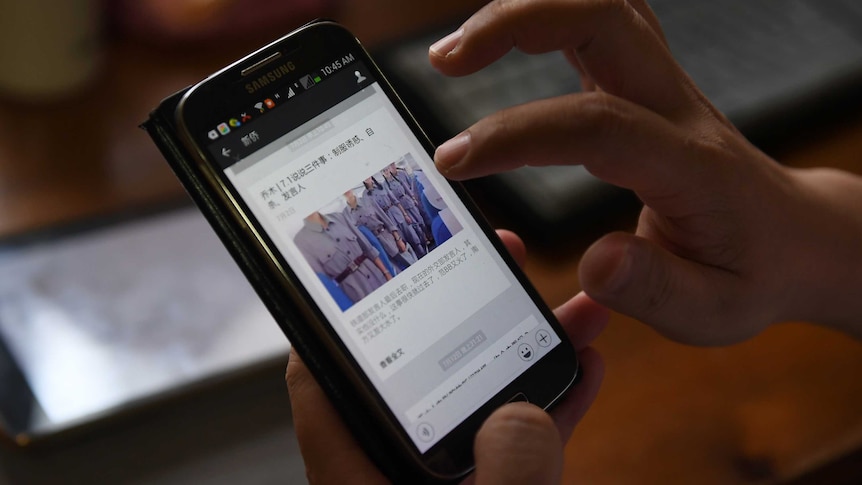 A man shows Chinese posts on a mobile phone.