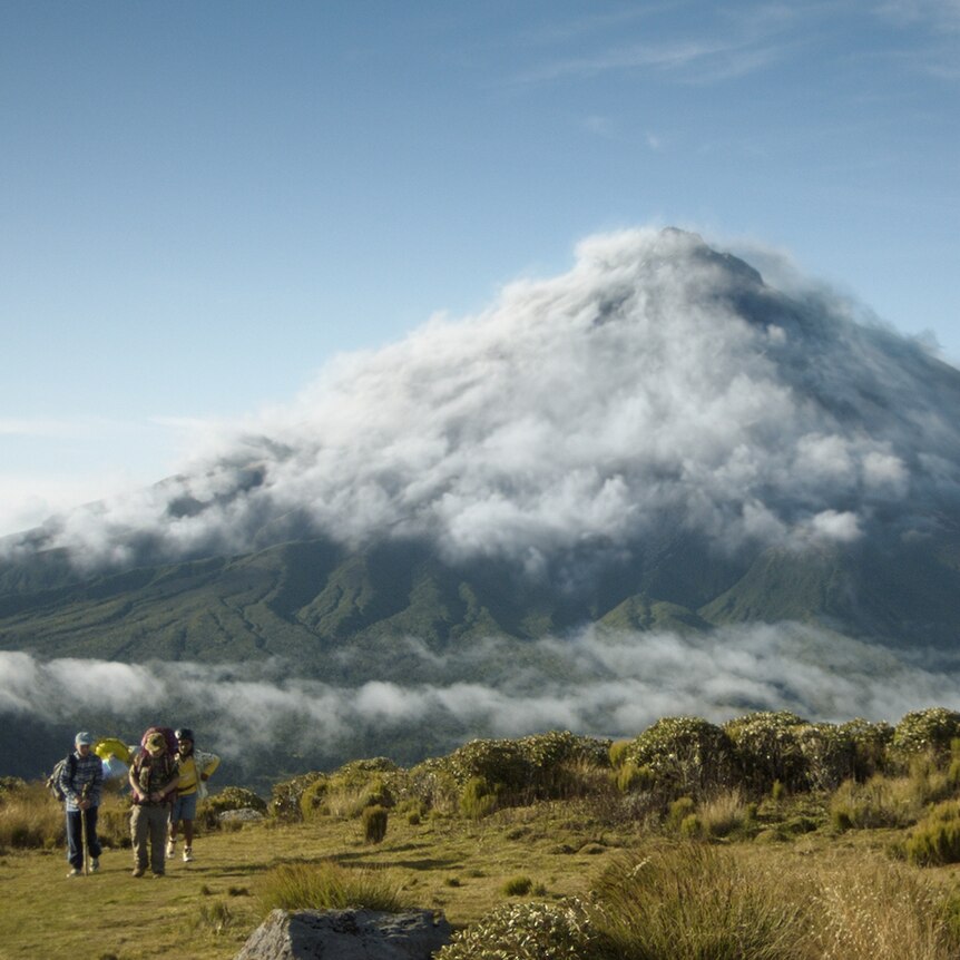 Three children approach a cloud covered mountain. One has a bicycle with a helium balloon attached