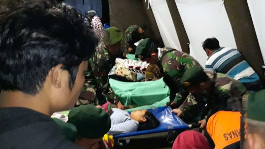 Indonesian soldiers tend to a woman injured in the earthquake at a makeshift hospital