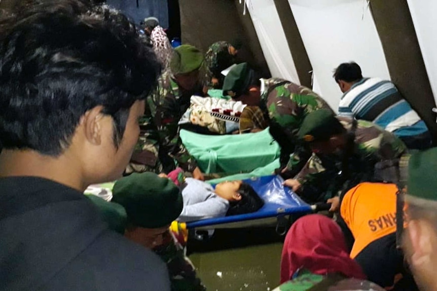 Indonesian soldiers tend to a woman injured in the earthquake at a makeshift hospital