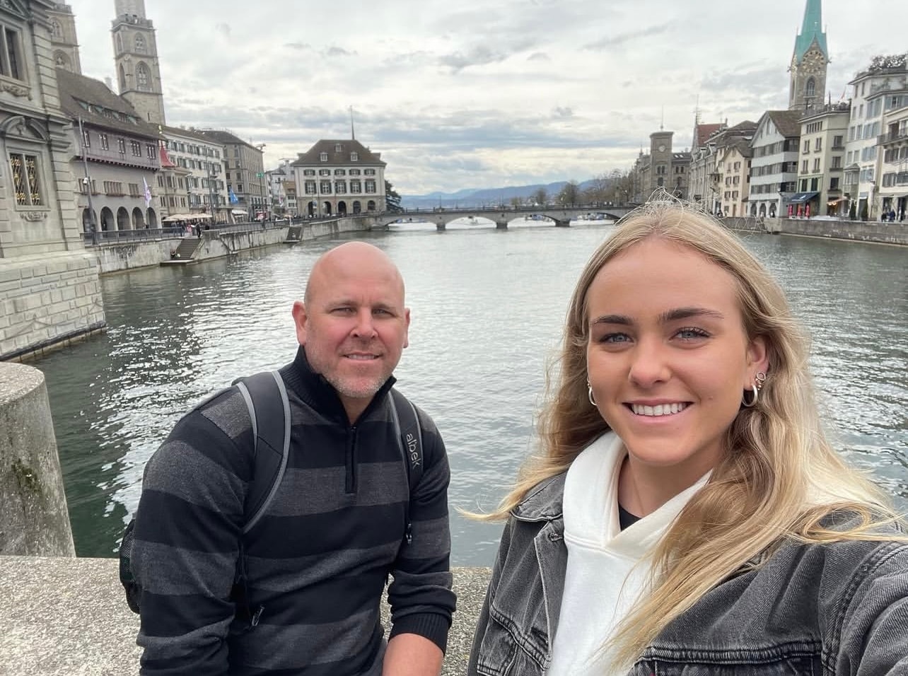 Um homem de meia idade parado em uma ponte ao lado de uma jovem.