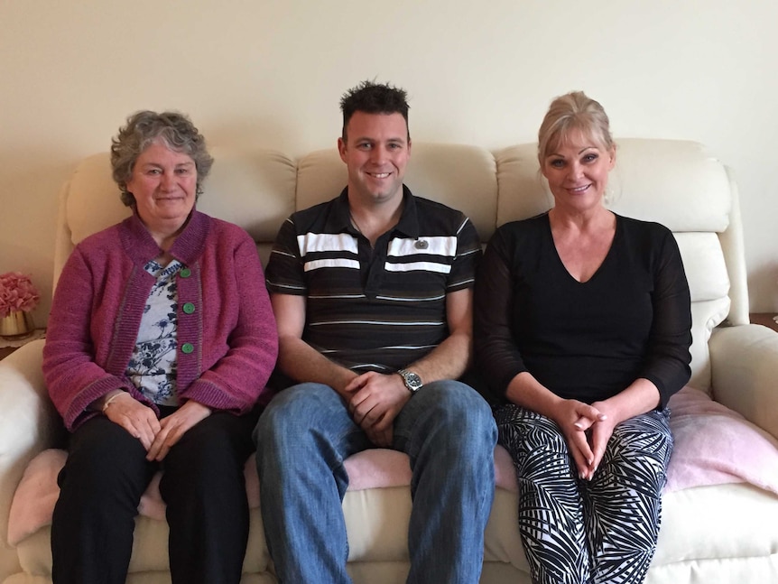 Three people sitting on a couch.