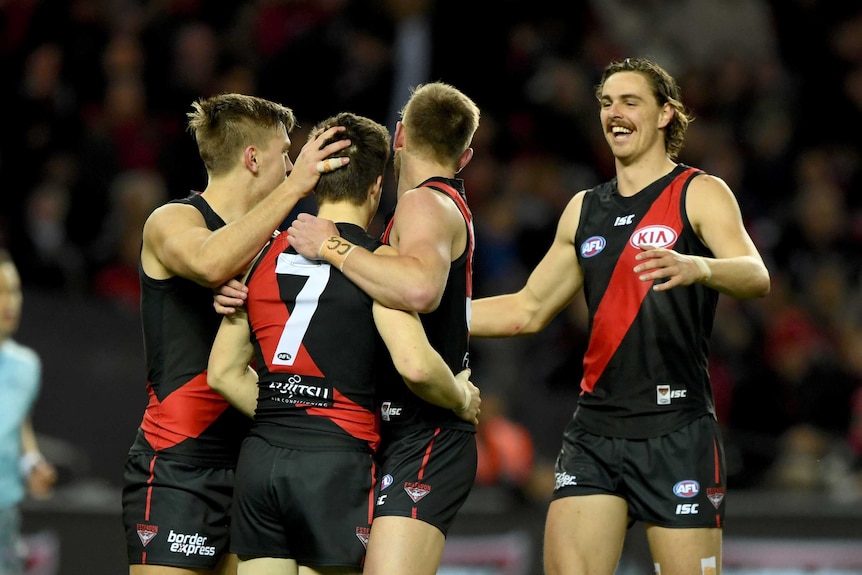 Essendon players celebrate a goal from Zach Merrett