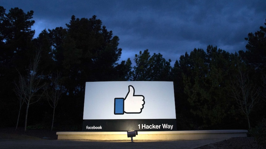 A billboard showing a thumbs-up under a dark sky.