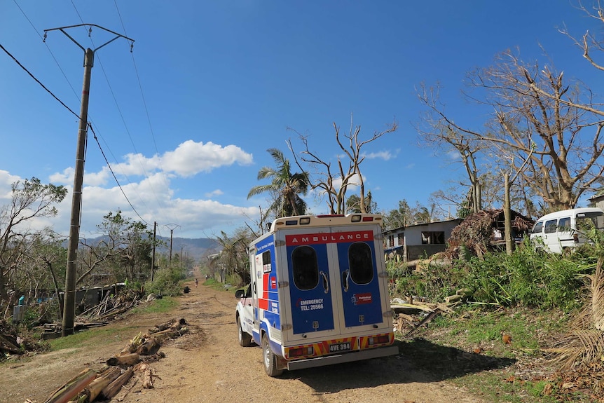 A Promedical ambulance drives through cyclone damage
