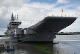 An aircraft carrier stands moored in port