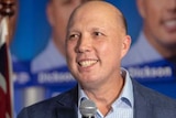 Federal Member for Dickson Peter Dutton smiles while holding a microphone.