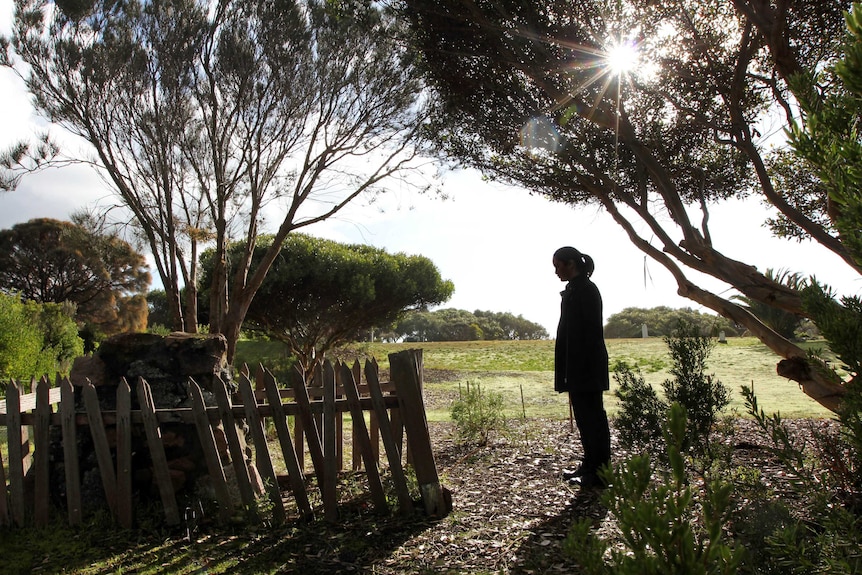 Woman standing at remote grave at cemetery