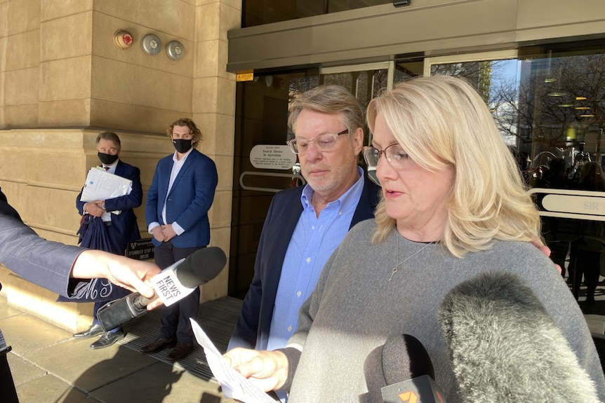 A man and a woman read a statement to the media outside court