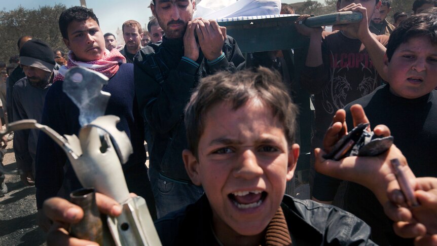Syrian boy holds remains of mortar and shells