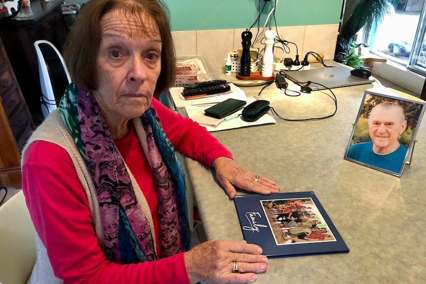 A woman sits at a table with a photo of her family.