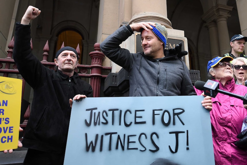 People holding signs celebrate the George Pell appeal decision.