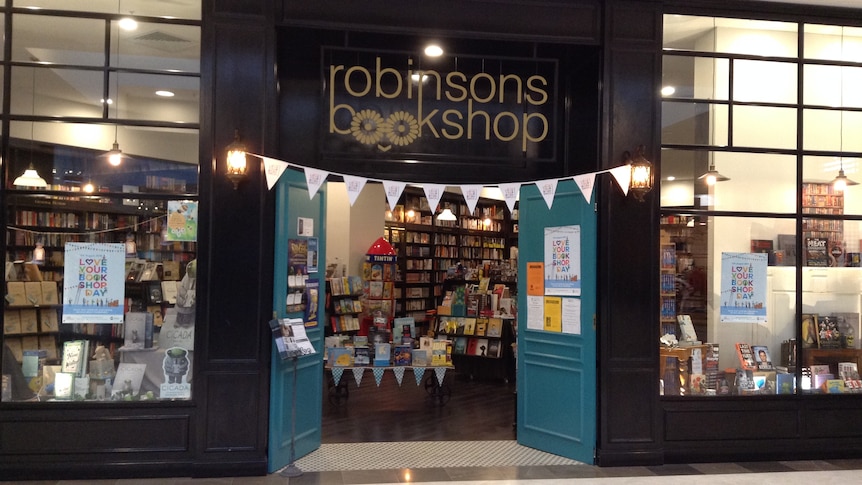 Robinsons bookshop front entrance, door open, books on display and flags underneath the name of the store