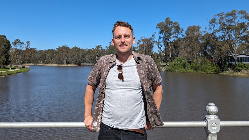 It's a sunny day and a smiling Kurt stands on a bridge looking at the camera