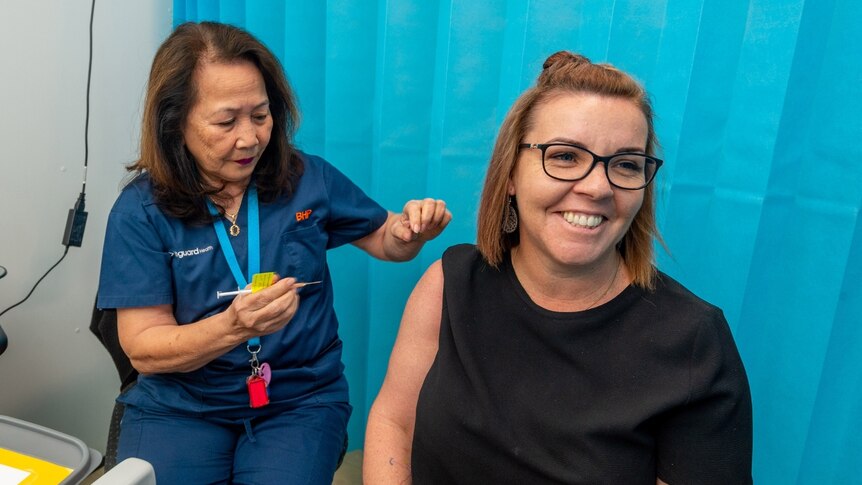 A nurse about to give a smiling woman a needle.