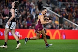 Brisbane Lions forward Charlie Cameron flexes his fists in celebration as he runs away after kicking a goal. 