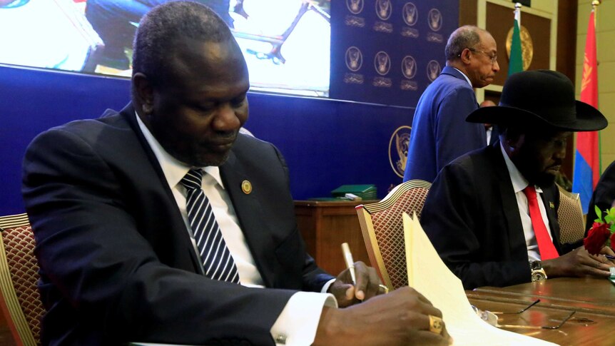South Sudanese rebel leader Riek Machar and South Sudan's President Salva Kiir sign documents.
