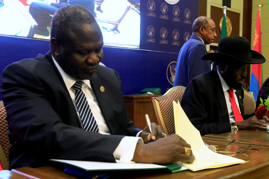 South Sudanese rebel leader Riek Machar and South Sudan's President Salva Kiir sign documents.