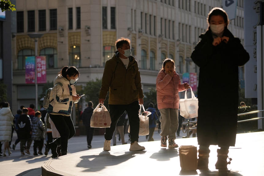 People wearing protective masks walk in a shopping district.