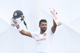 Dinesh Chandimal holds up his bat and his helmet and smiles
