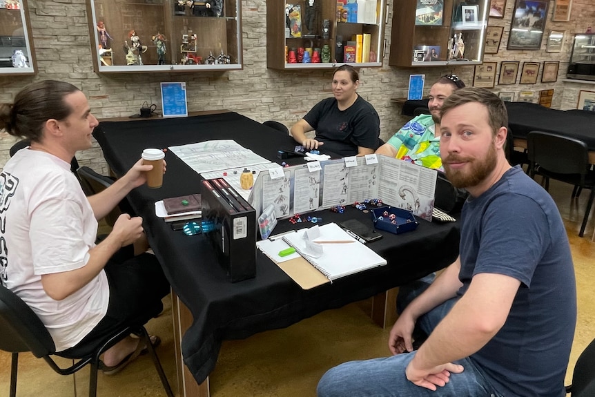 A group of players get ready to play Dungeons and Dragons sitting around a table.