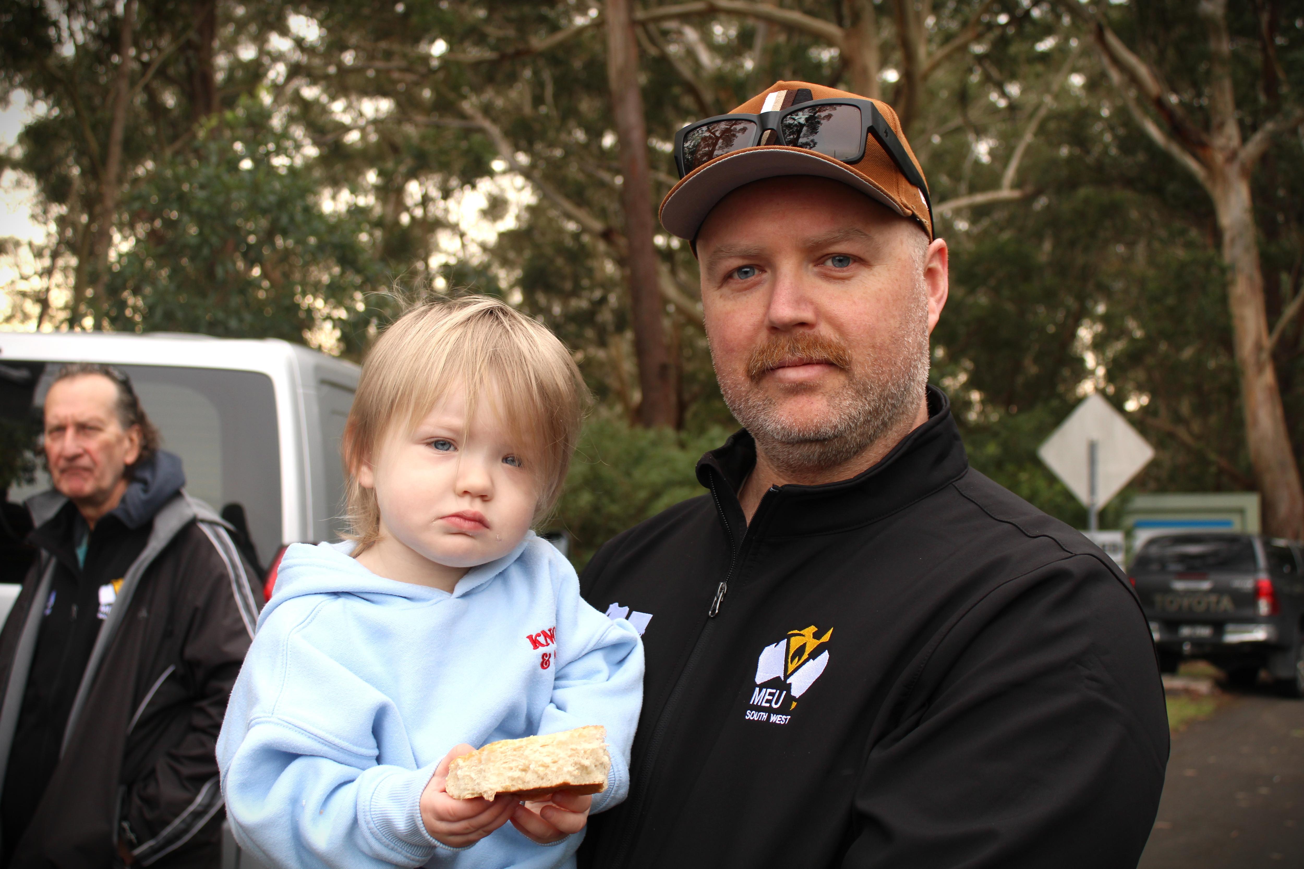 Niño pequeño sosteniendo un rollo que tiene un hombre con bigote y camionero.