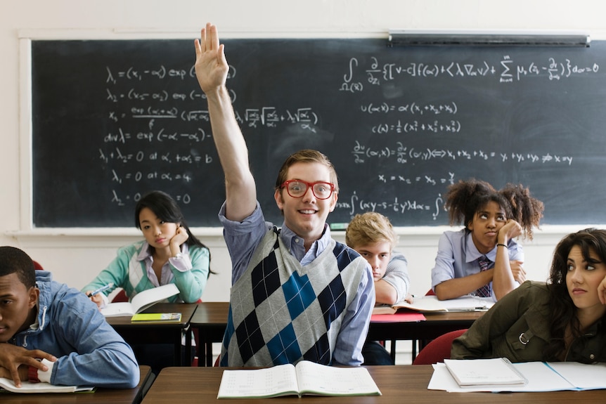 Teenage boy with glasses eagerly raising his hand in class