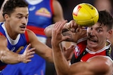 Josh Battle handballs above his head as a Bulldogs player approaches to tackle him