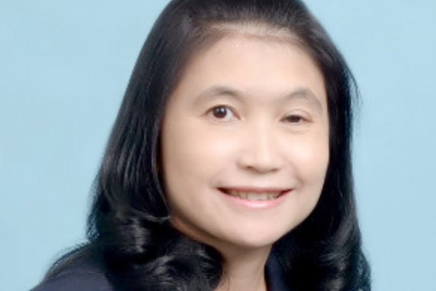 A close up of a woman with dark hair and dark eyes smiling