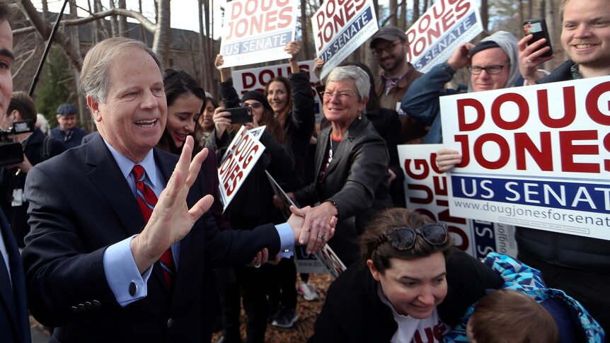 Democratic candidate Doug Jones greets supporters holding signs of his name.