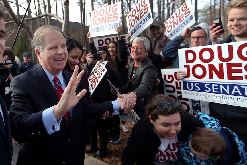 Democratic candidate Doug Jones greets supporters holding signs of his name.