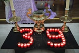 Small candles at a church alter are arranged in to the number 39