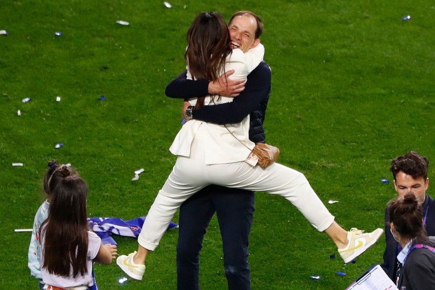 Football coach embraces wife with a big hug after winning a championship match