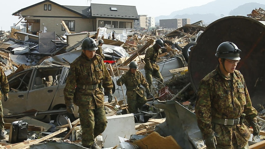 Soldiers from Japan's Self Defence Force search for victims among the rubble (Reuters)