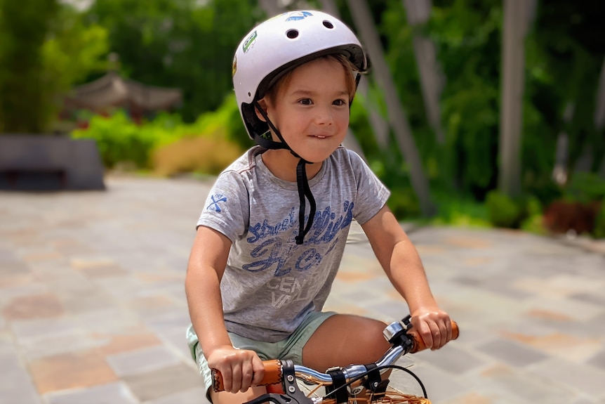 A young boy with a helmet riding a bicycle