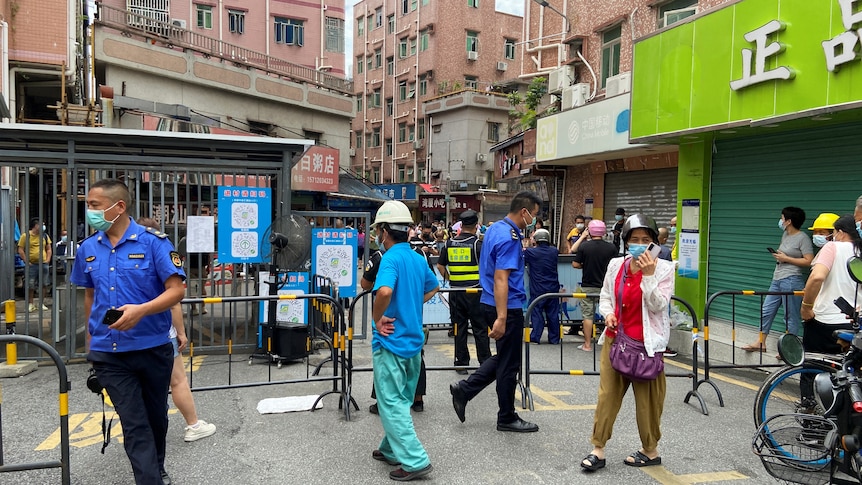 Security guards stand at an entrance to a closed residential compound.