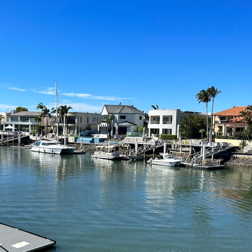 Row of large homes along waterfront with boats moored out front
